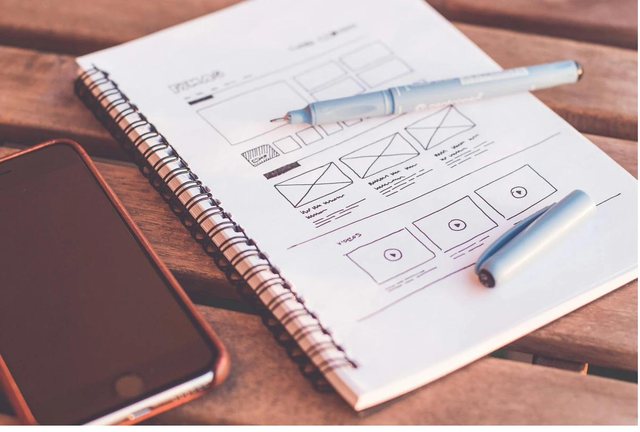 Hand-drawn wireframes in a notebook next to a phone